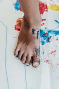a child’s foot dipped in paint to make footprints on a big sheet of white paper as an example of ways to keep your preschooler engaged at home 