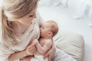 mom holding baby to breastfeed