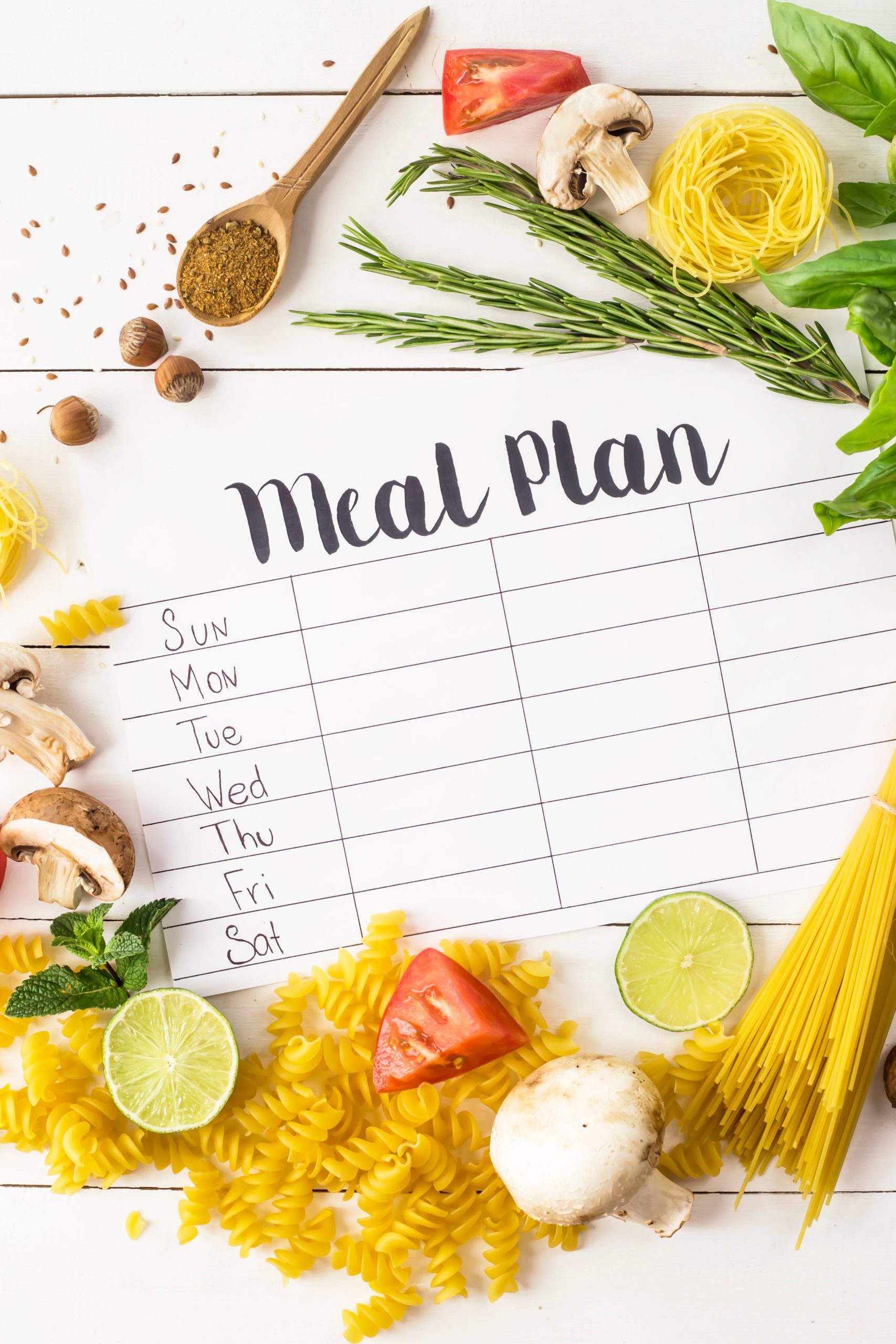 Meal planning list surrounded by dried pasta and vegetables