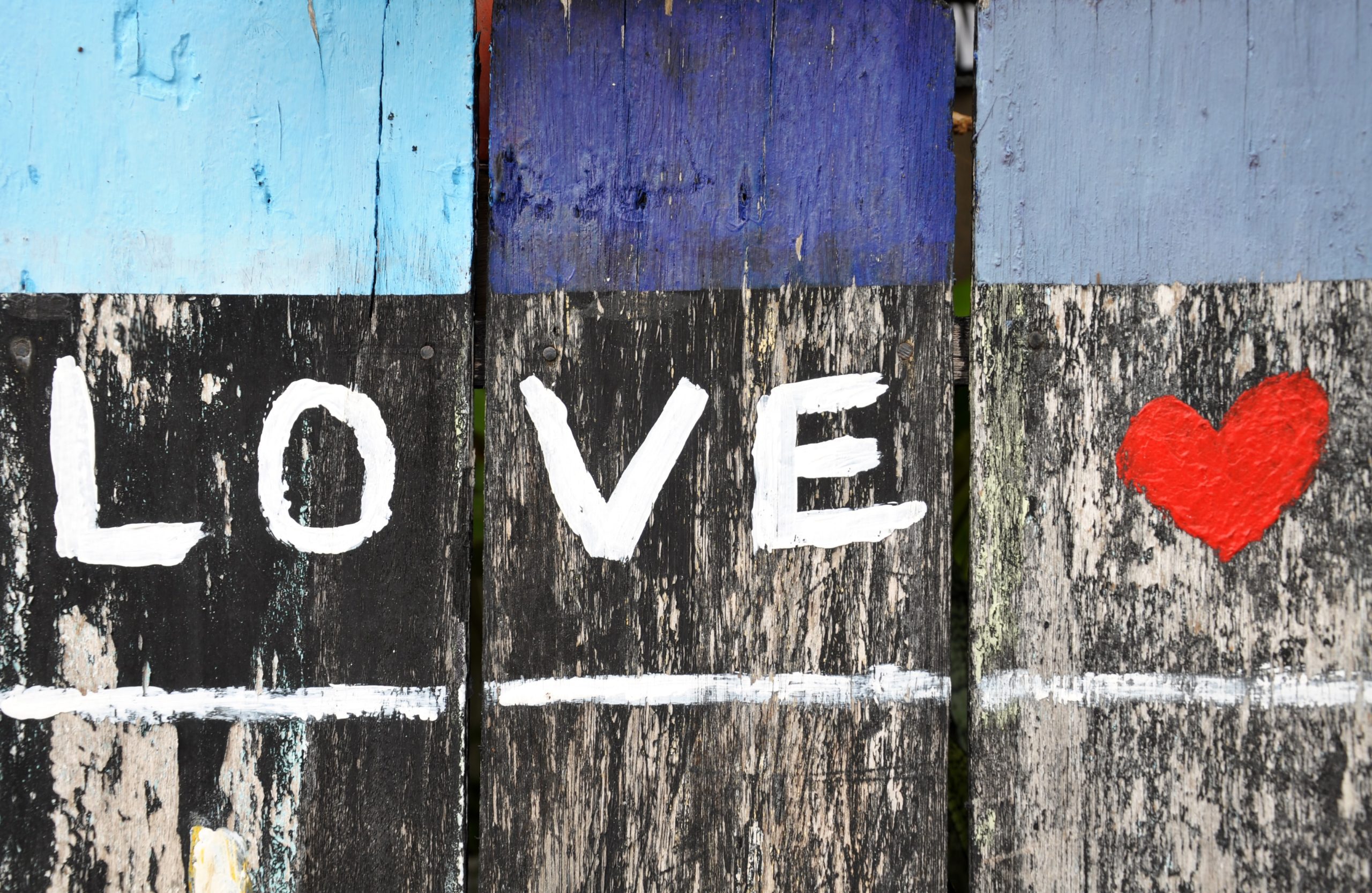 LOVE written in white paint with a red heart on a wooden fence