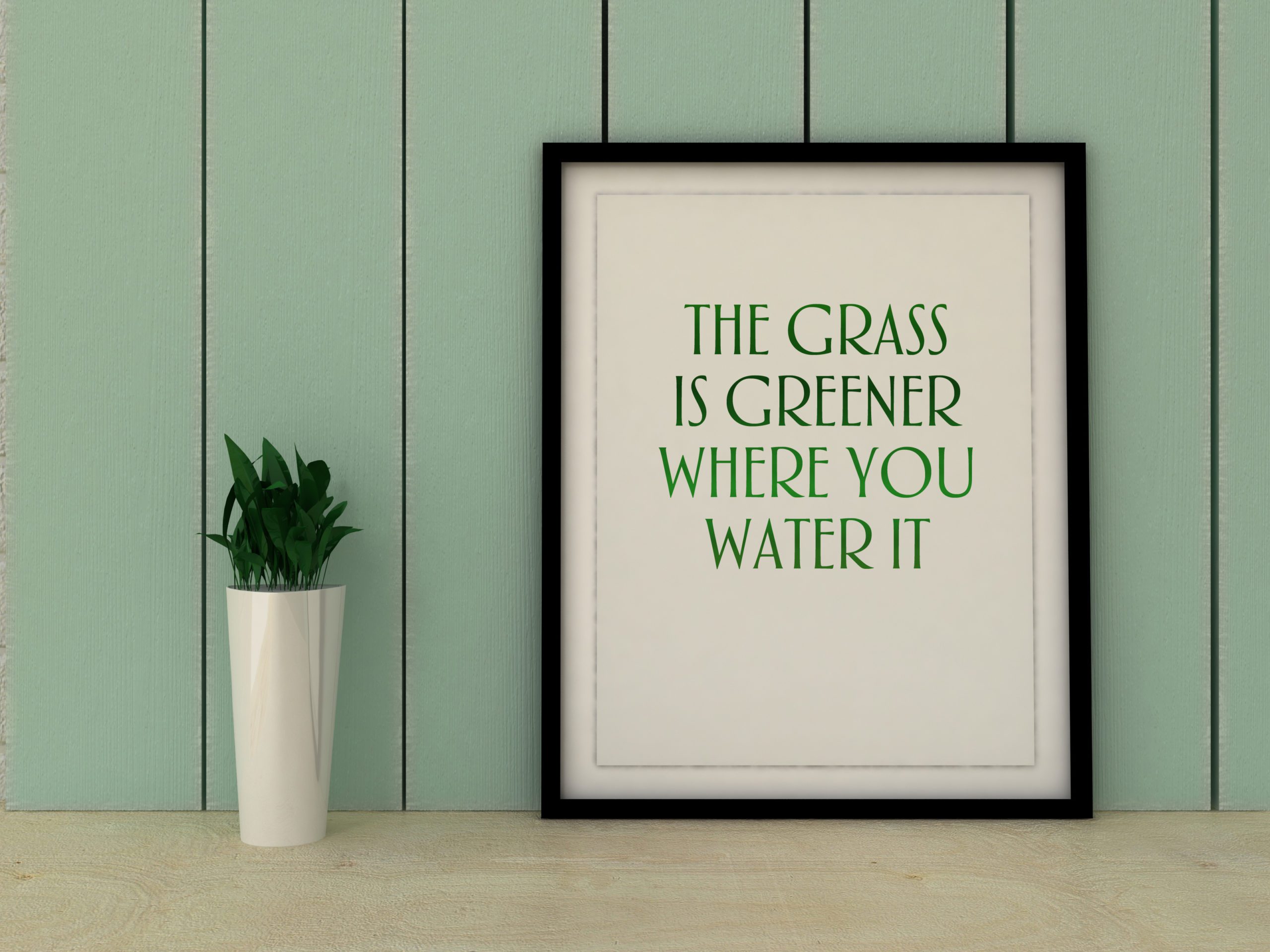 a black framed quote which says, "The Grass is Greener Where You Water It"