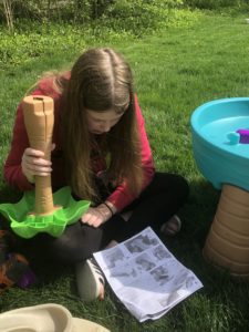 a girl assembling a toy with the instructions outside in the grass