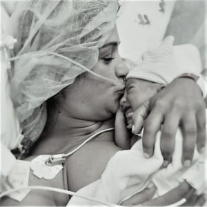 A black and white photo of a mom kissing her newborn baby immediately after he is born, symbolizing that when this woman became a mom, a new purpose emerged