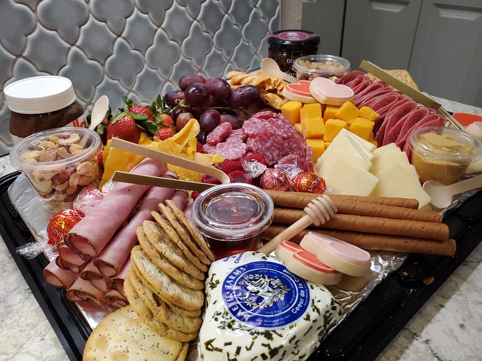 charcuterie board full of meats, cheeses, crackers, and spreads