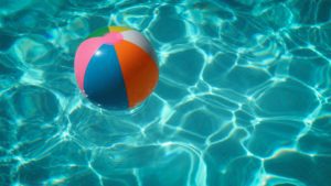 a close up of a beach ball floating on the surface of a pool, part of the 2020 essentials list for summer