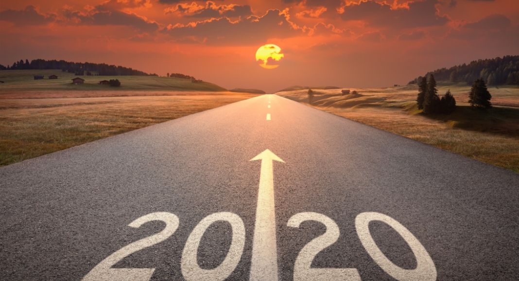 a road with 2020 painted on it with a painted arrow pointing to the sunset in the distance