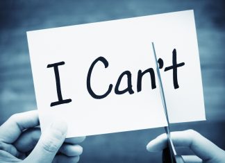 a black and white photo of the words, "I Can't" on an index card with two hands, cutting off the "t"