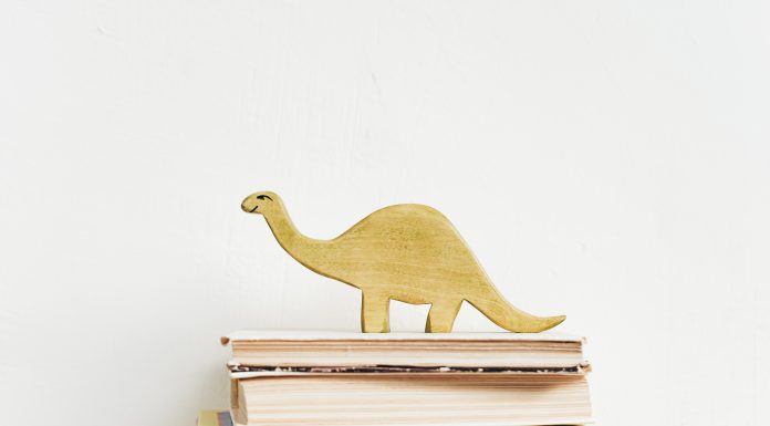 a stack of books with a wooden dinosaur on it