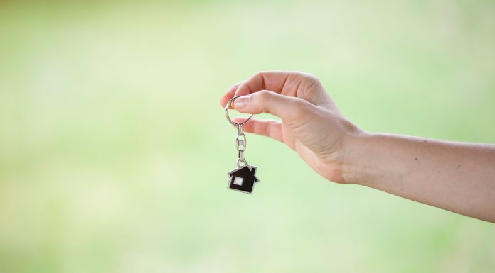 a close-up of a hand holding a house shaped key chain