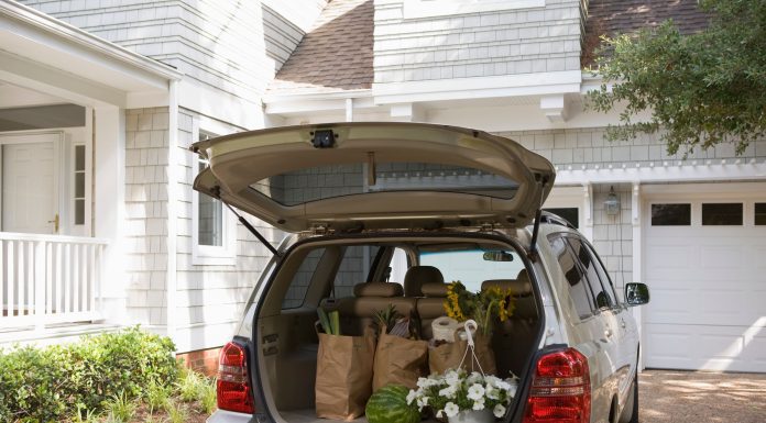 a minivan parked in a driveway with the trunk open and groceries in the back