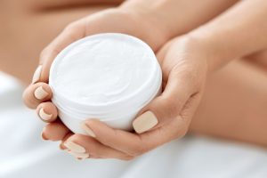 clean beauty hand lotion in an open jar in the hands of a woman