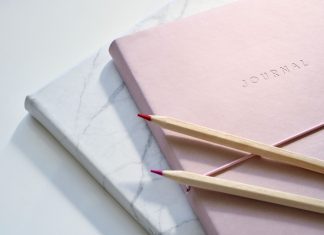 two journals with colored pencils laying across the top
