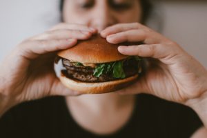 close up of a man eating a burger