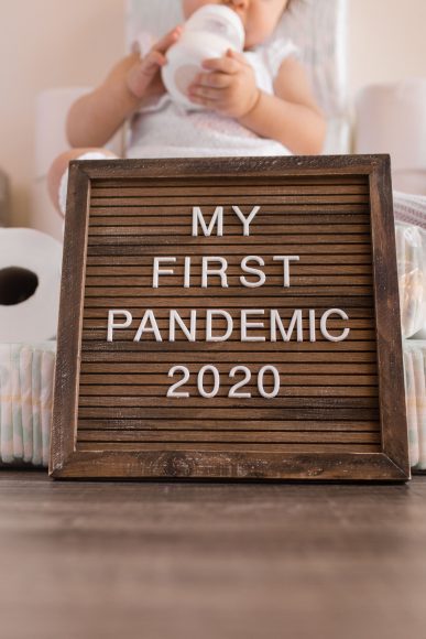 a letter board with the message, "My First Pandemic 2020” as a baby sits in the background