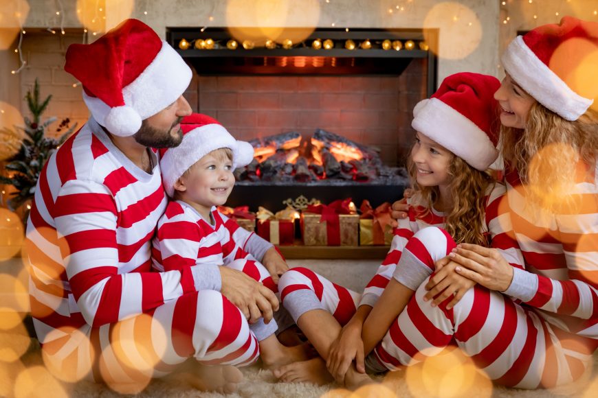 a family sitting around the fireplace in holiday pajamas