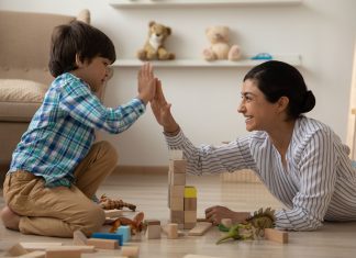 a mom and son building with blocks on the floor as they high five each other