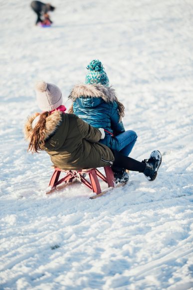 two girls sledding down a hill