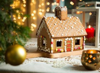 a gingerbread house on a table near a Christmas tree