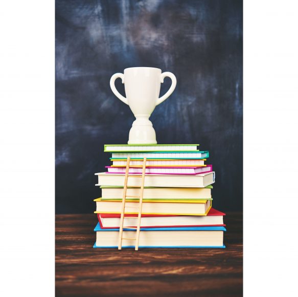 a stack of books with a trophy on top