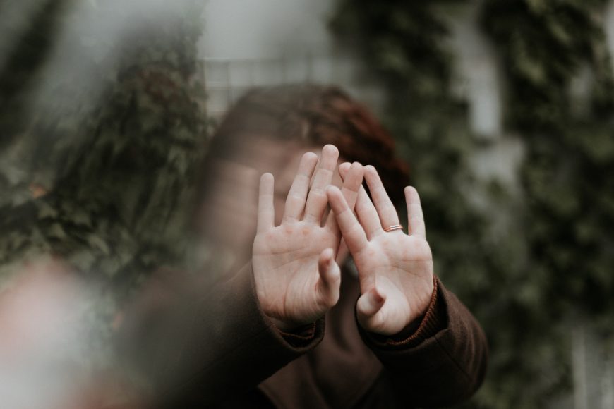 a girl hiding her face behind her hands in shyness