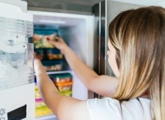 a woman reaching in the freezer for a freezer meal