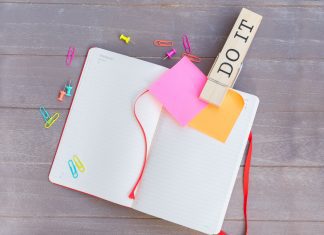a journal open with sticky notes on the pages, and a clip bookmark that says, “do it'