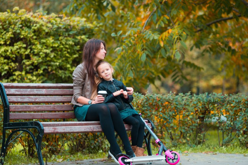 Adorable little girl with mom enjoy fall day in autumn park outdoors