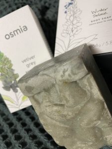 A bar of hand-crafted vetiver gray soap from Osmia Organics and two of their recyclable boxes.
