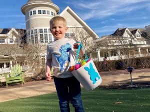 a young boy with an Easter basket full of eggs in front of the Magic House in St. Louis