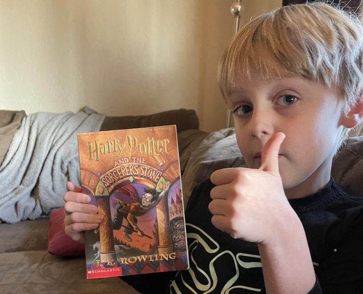 Josh holding his Harry Potter book and giving it a thumbs up.