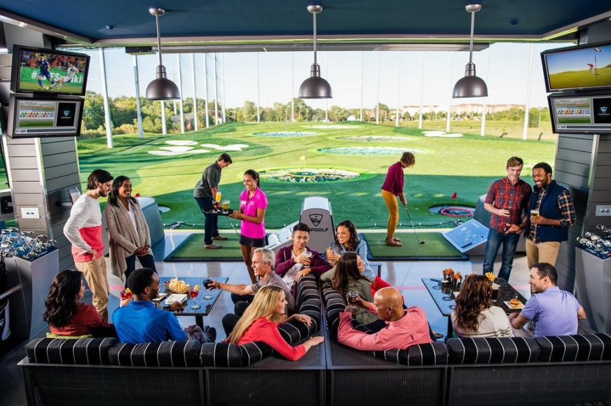 adults in a bay at Top Golf St. Louis enjoying a date night out