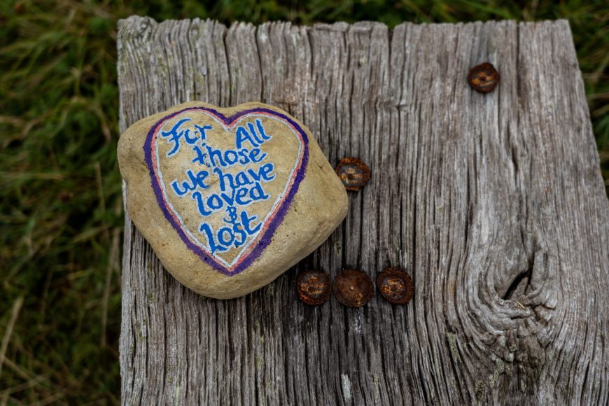 a rock with a painted heart and the words, “for all those we have loved and lost” representing grief