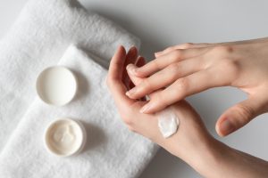 a woman moisturizing her hands with lotion