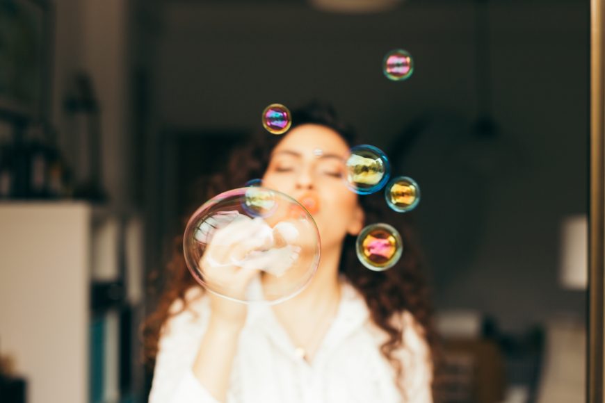 a woman blowing bubbles indoors