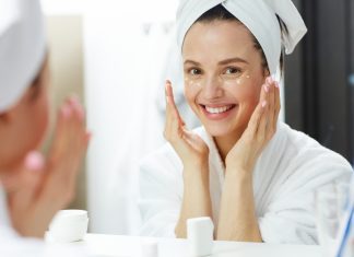 a woman in a white robe with her head wrapped in a towel as she does her daily skincare routine