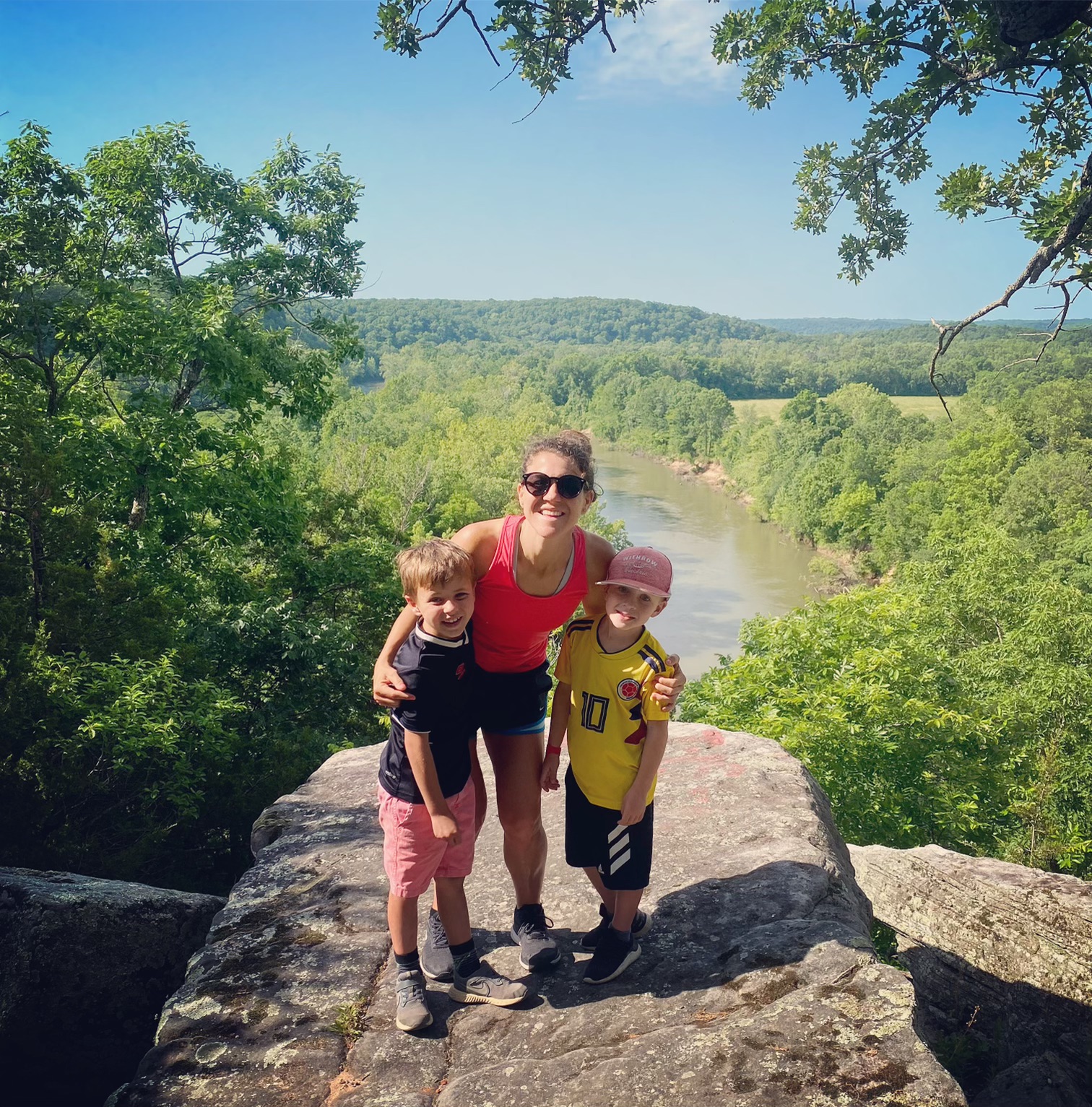 a mom and her two boys on a rock overlooking a river