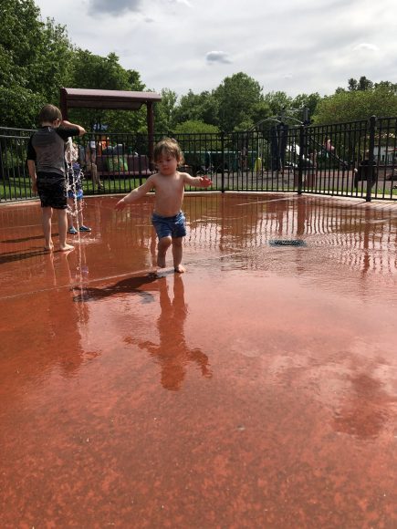 a young boy playing in a splash pad at a park