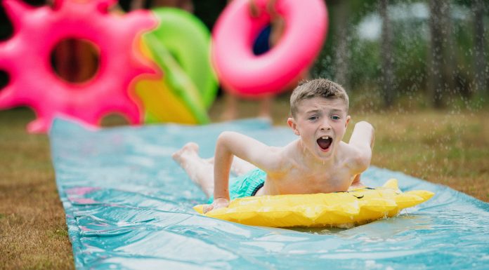 a boy sliding on a slip ’n slide in his yard