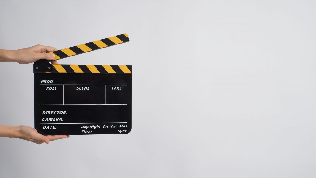 two hands holding a clapper board on a white background