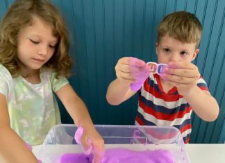 a boy and a girl playing with soap foam in a plastic tub as sensory play