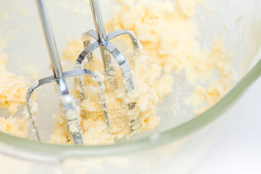 a hand mixer in a bowl with butter and sugar