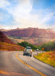 a car viewed from behind as it goes road tripping down a scenic road