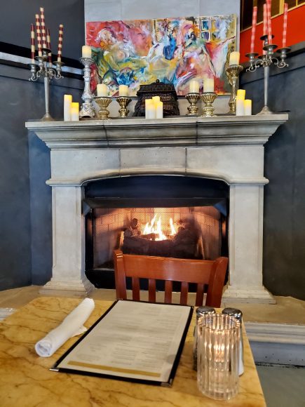 a fireplace lit up with artwork and candles surrounding it