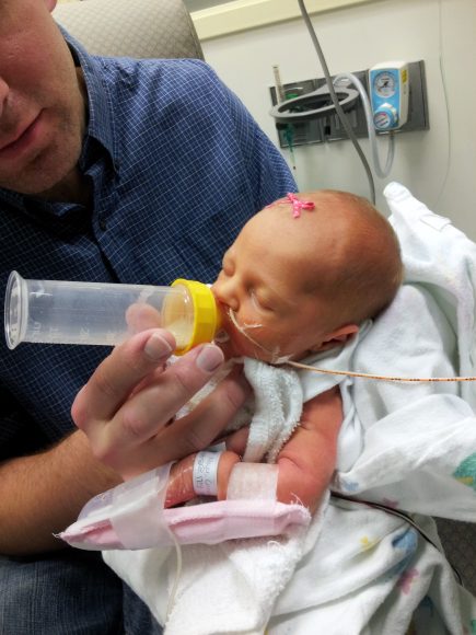 a dad feeding a bottle to his premature daughter in the NICU