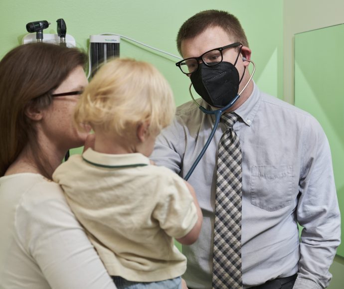 Dr. Theodore Kremer with Esse Health Pediatrics, in an exam room with a toddler and his mother