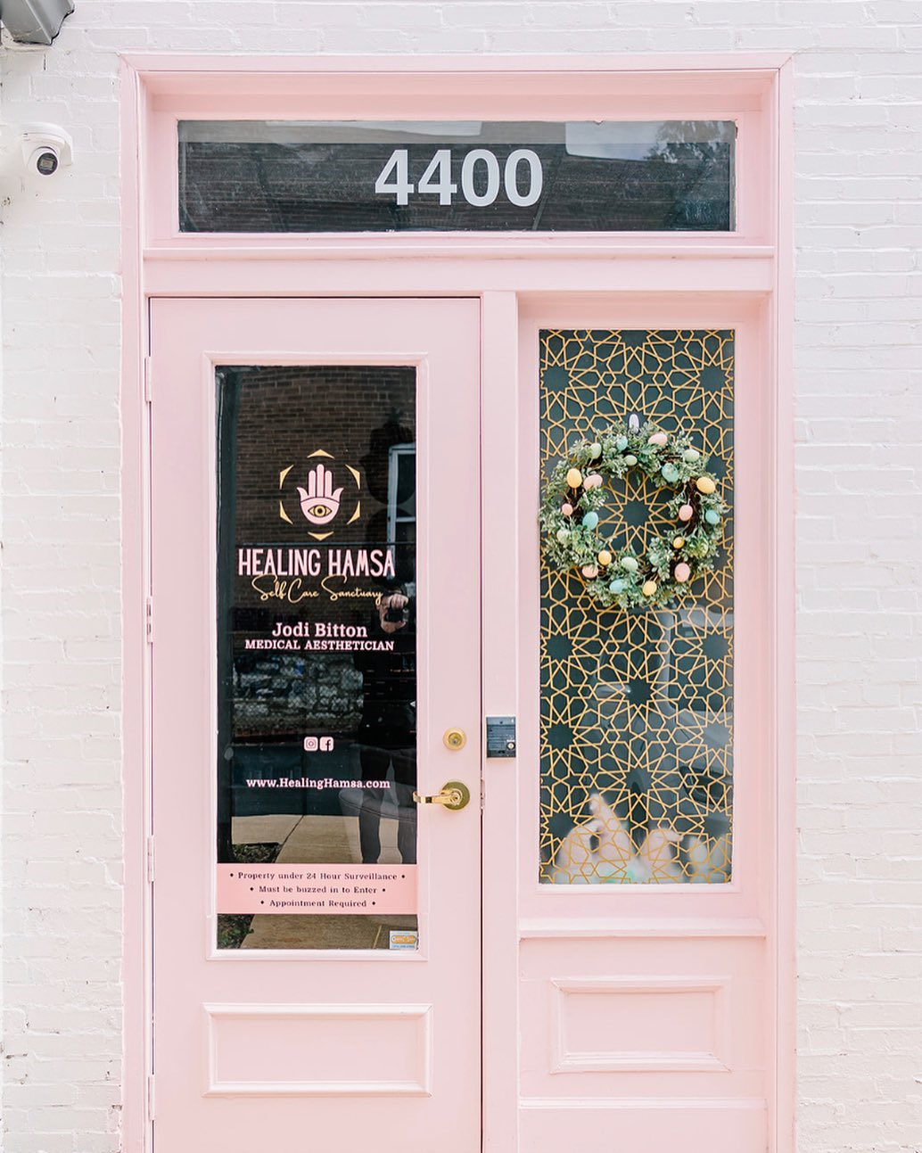 a close up of a pink front door with the Healing Hamsa logo on it in St. Louis, Mo