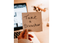 a woman holding a post-it note that says, “take a breather”