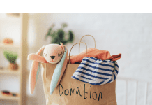 a paper bag with the word, “donations” written on it as clothing and stuffed animals spill out the top